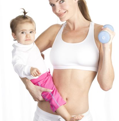 Junge Mutter in weißem Trainingsoutfit mit Baby auf dem Arm